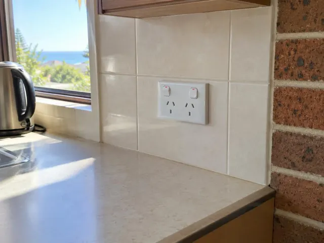 White double power point on a tiled kitchen splashback beside a benchtop and window in Collaroy