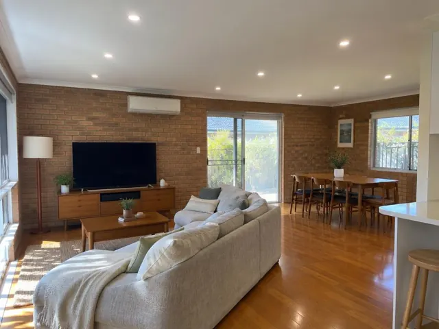 Living room ceiling with recessed LED downlights, brick walls, sofa, TV and dining area in Brookvale